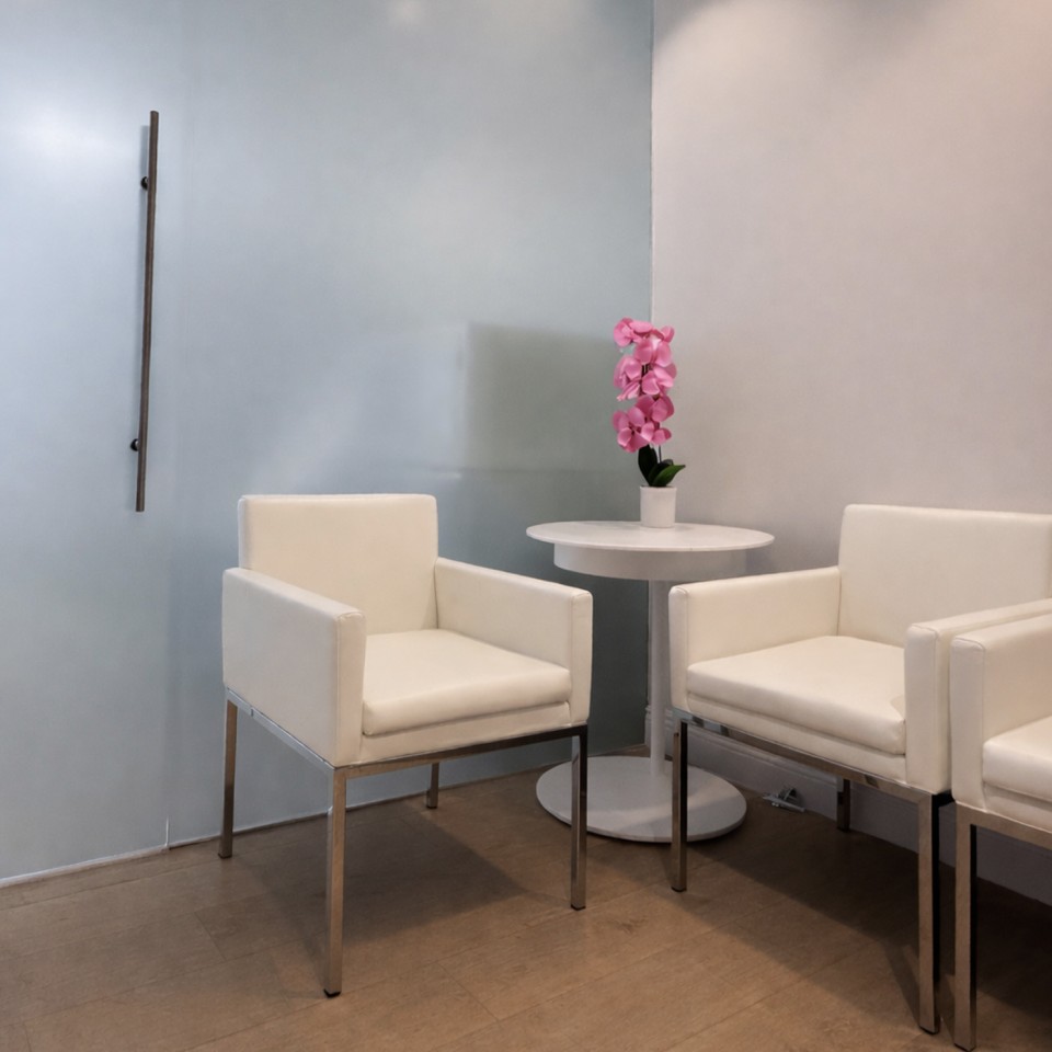 Three white chairs around a small round table with a rose orchid in a pot;