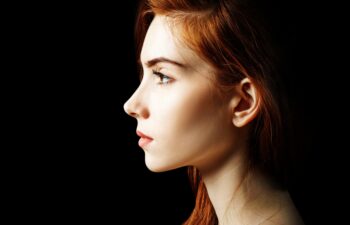 Beauty portrait of redhead woman. Over black background.