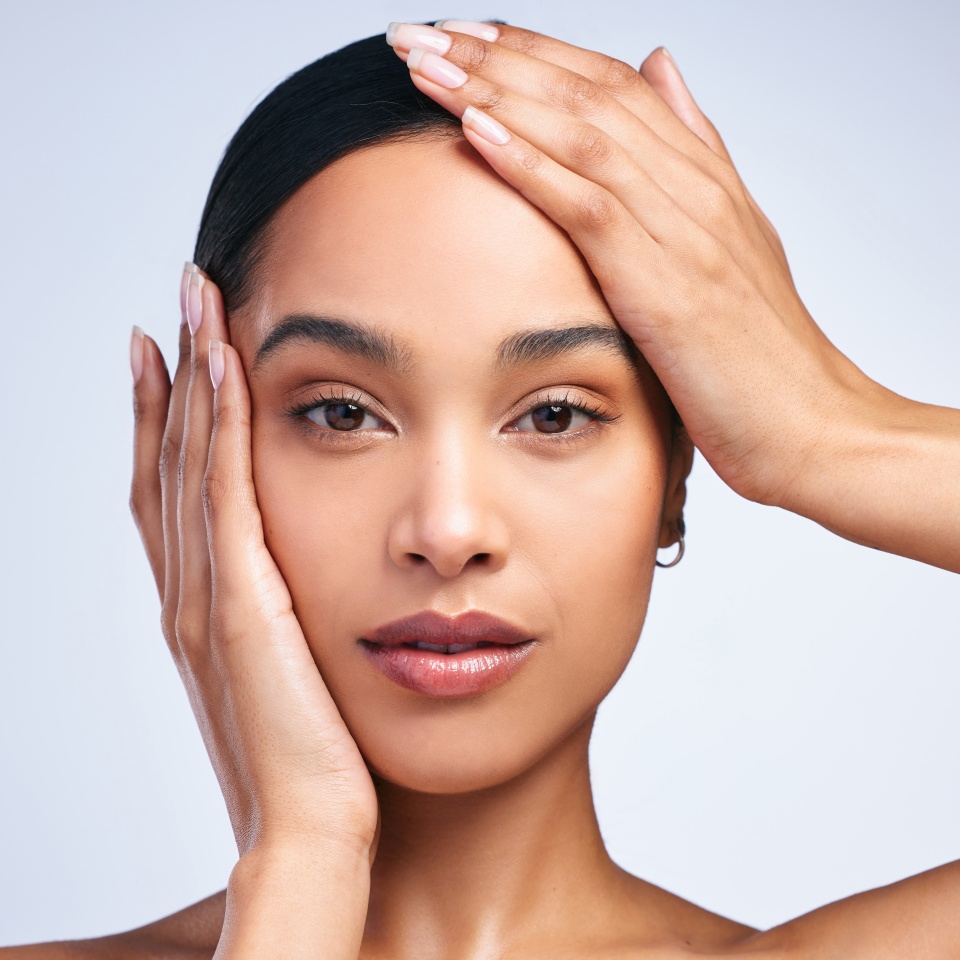 Portrait, model girl and hands on face in studio for skincare, dermatology and glow. Beauty, woman and confidence or pride for cosmetics and wellness by white background for foundation and aesthetics